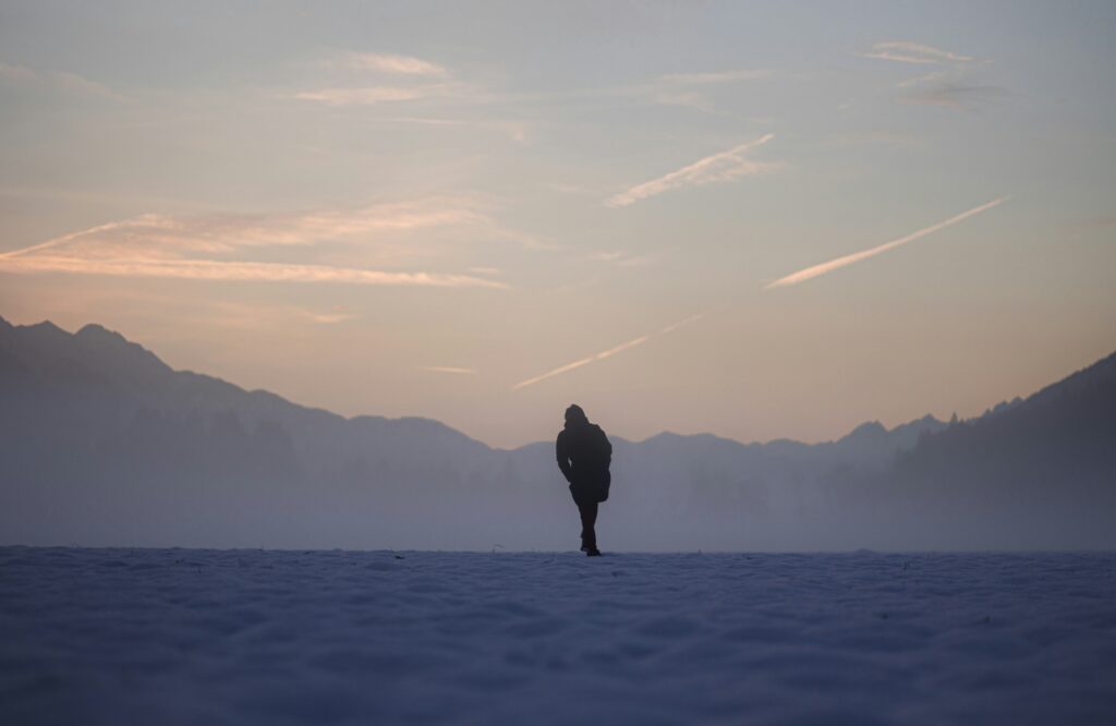 person walking into sunset or sunrise